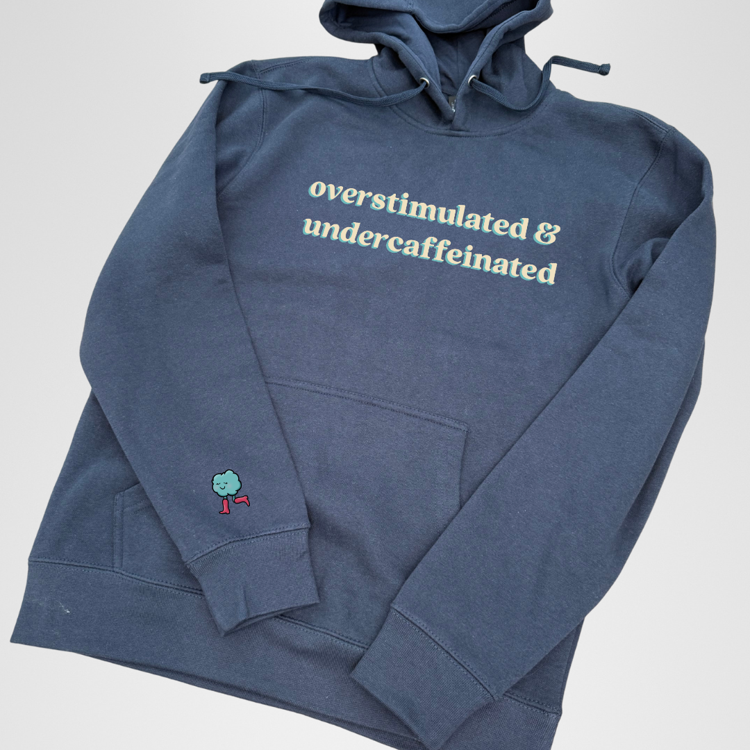 Blue hoodie with text 'overstimulated & undercaffeinated' on a light gray background