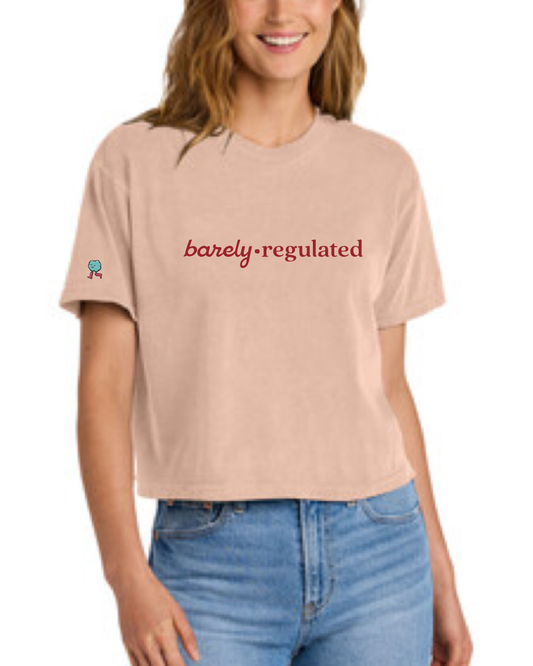 Person wearing a peach t-shirt with 'barely regulated' text in red and logo on sleeve