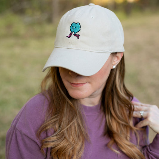 Person wearing a beige cap with a blue and pink design outdoors