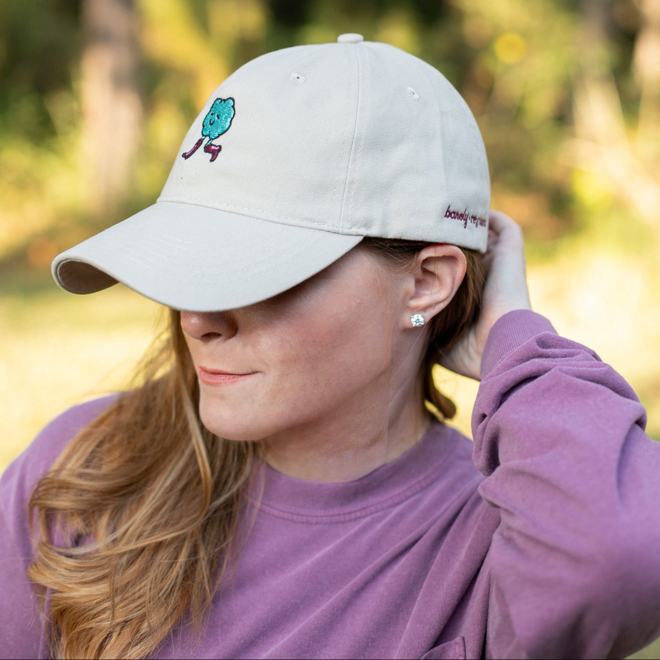 Woman wearing a beige cap with a logo, outdoors