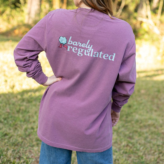 Person wearing a purple long-sleeve shirt with 'barely regulated' text outdoors.
