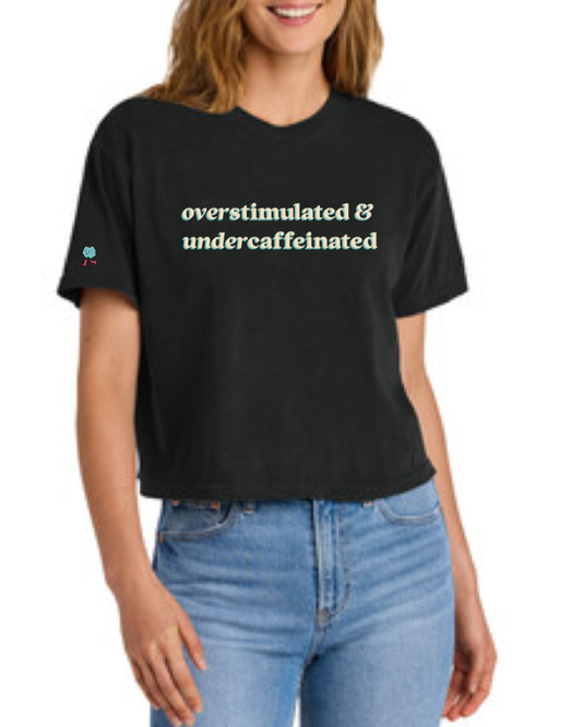 Person wearing a black t-shirt with 'overstimulated & undercaffeinated' text.
